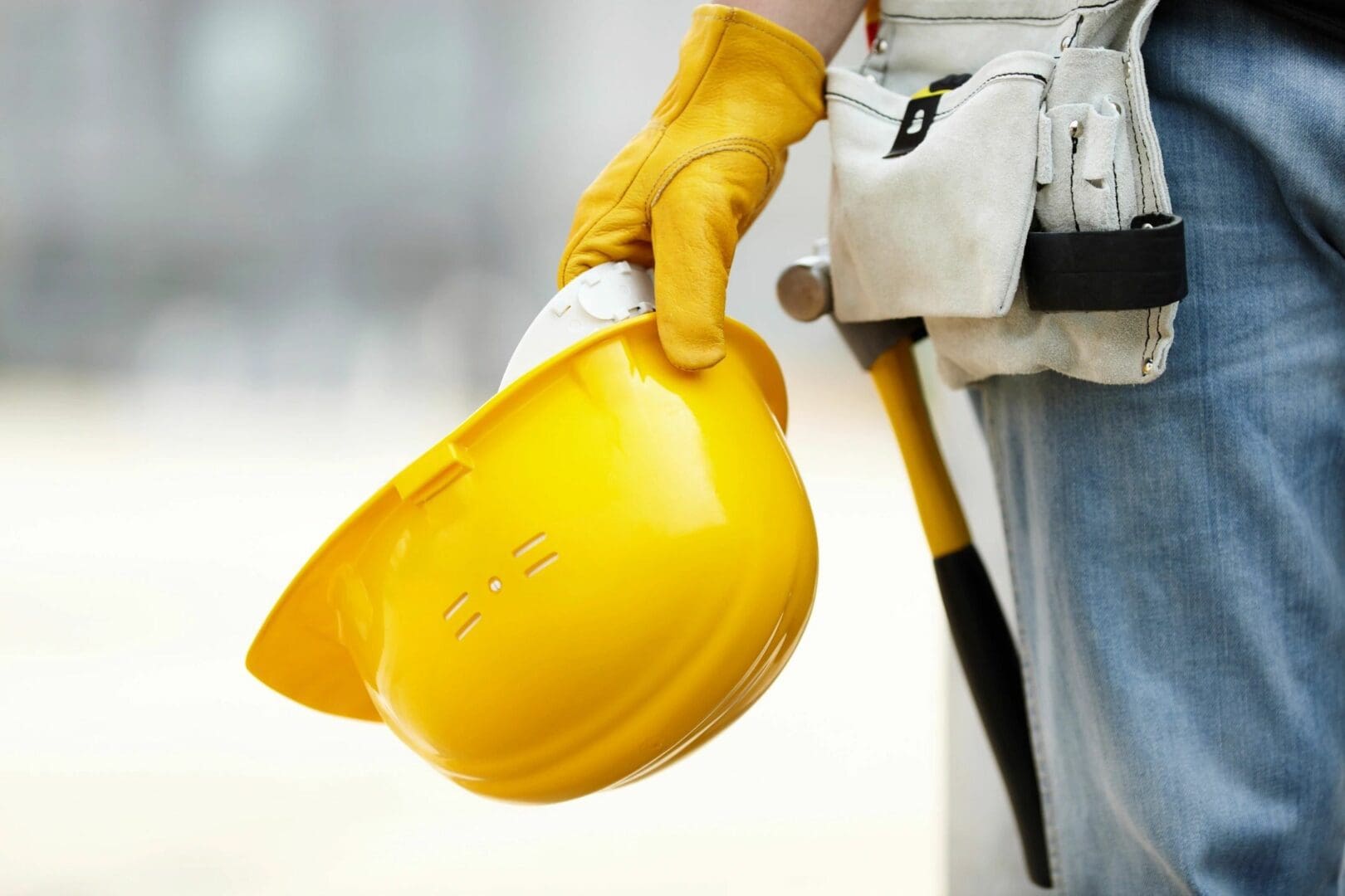 A person holding a yellow hard hat and wearing gloves.