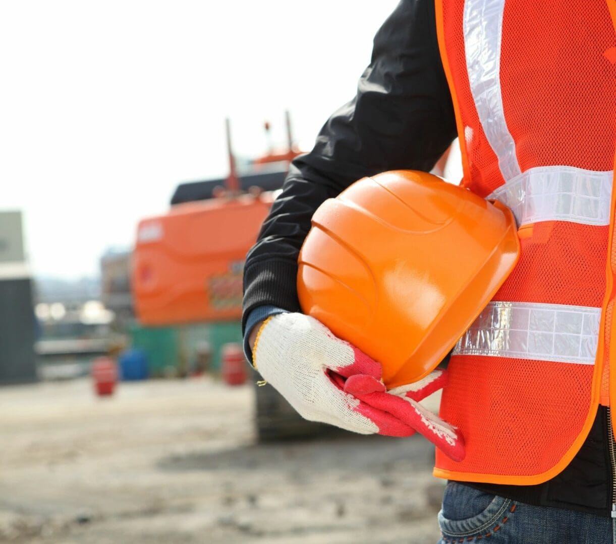 A construction worker holding his hard hat and gloves.