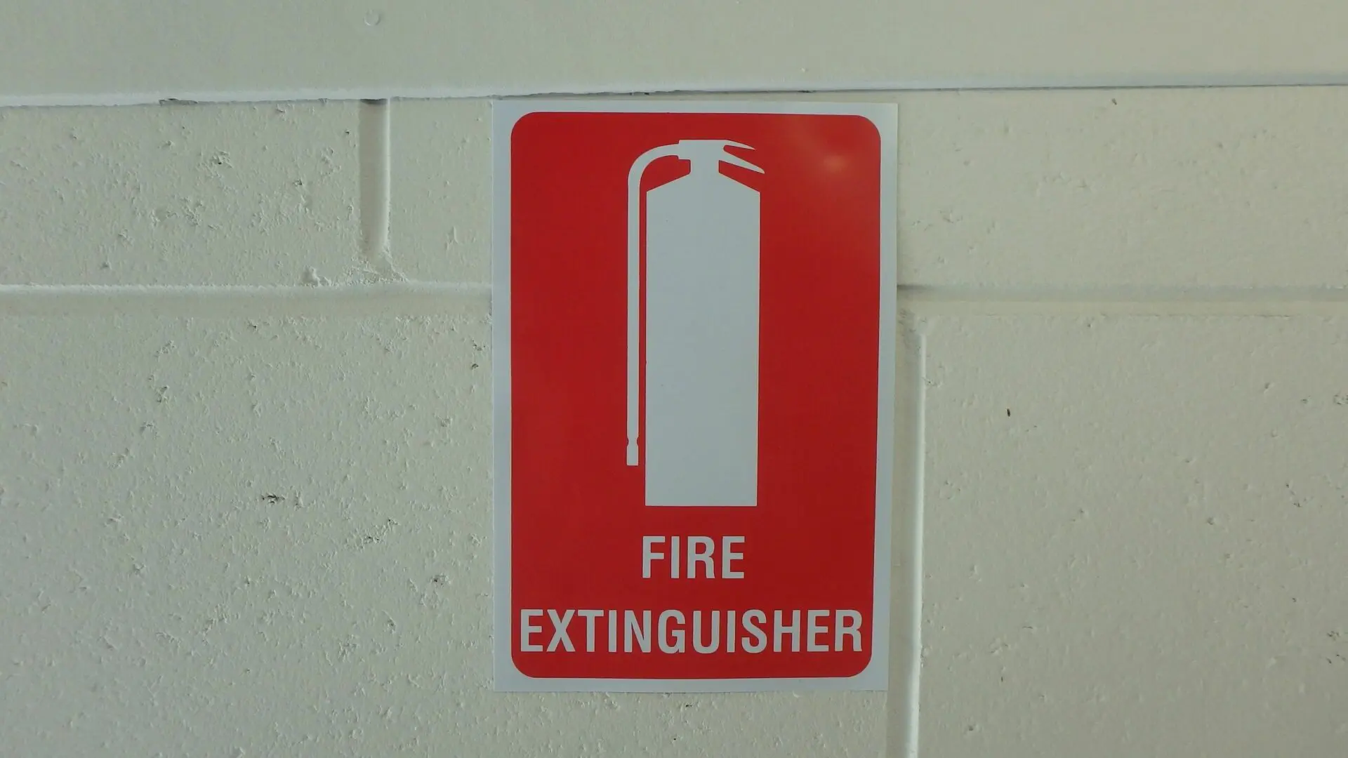 A fire extinguisher sign on the side of a wall.