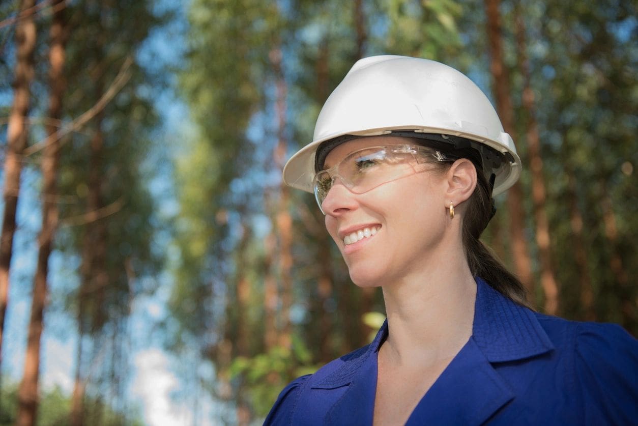 A woman wearing a white hard hat and glasses.