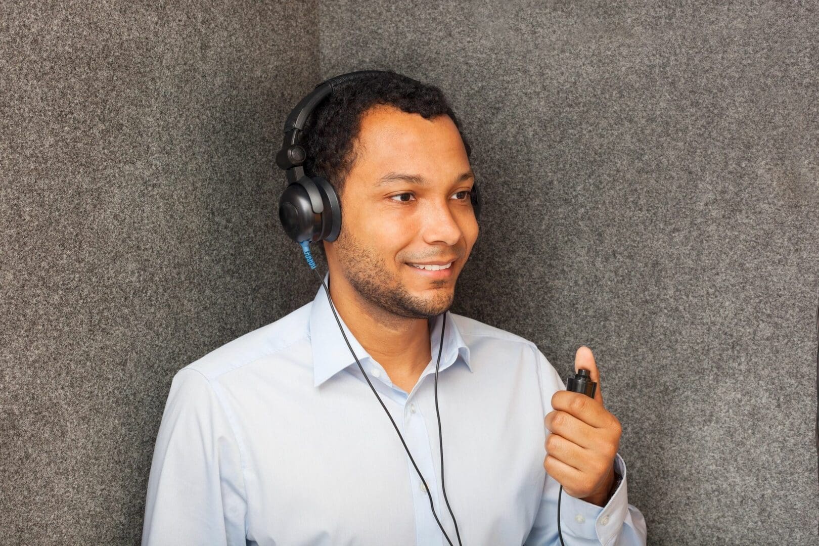 A man with headphones on holding a cell phone.